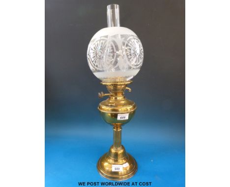 A brass oil lamp with etched globe type shade 