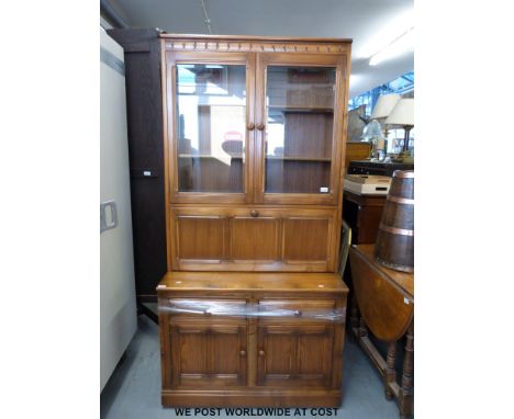 An Ercol dresser/ secretaire unit with glazed cupboard above drop flap to top and two drawers above cupboard to base (W98 x D