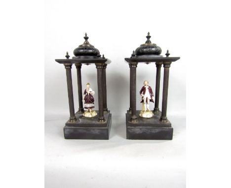 A pair of Victorian black slate and brass pagoda's each enclosing later ceramic figures