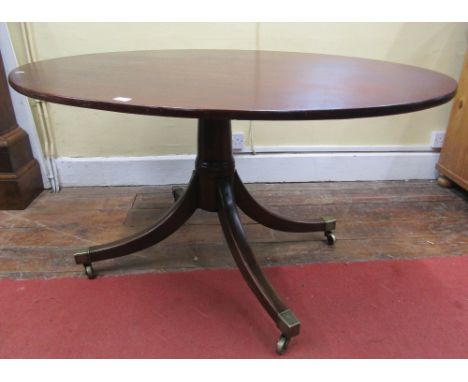 A Georgian mahogany tilt top breakfast table of oval form, raised on a central turned pillar with swept tripod, with brass ca