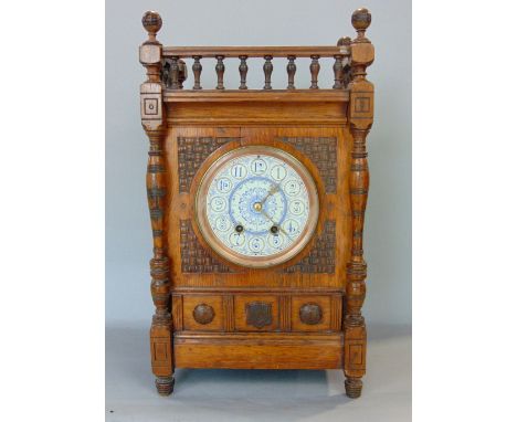 An Arts &amp; Crafts oak cased mantle clock, painted enamelled dial and twin train movement, the case with typical stylised c