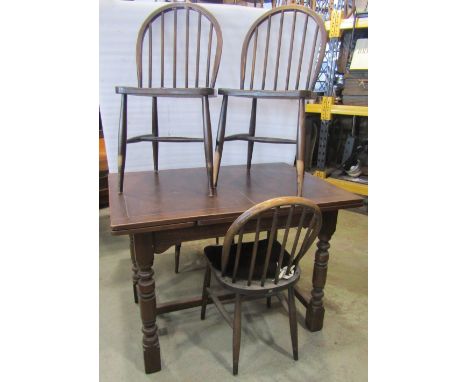 A reproduction oak drawleaf dining table in the old English style raised on four turned baluster supports united by a H shape