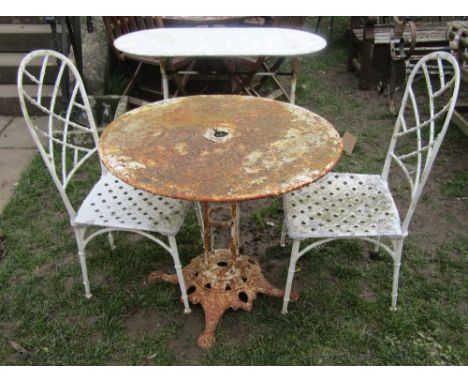 A vintage weathered garden terrace/bistro table with circular tin top and pierced cast iron base with lions paw feet, togethe