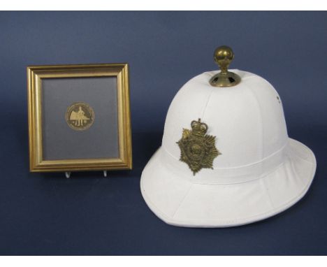 A Royal Marines white pith helmet with applied brass insignia, together with a framed medallion commemorating the Royal Marin