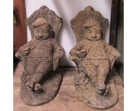 A pair of weathered cast composition stone novelty garden ornaments in the form of snoozing gnomes seated/reclining in throne