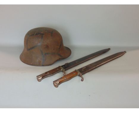 A WWII German military helmet together with two WWI German bayonets by Mauser Flischtel and Sachs, with steel scabbards