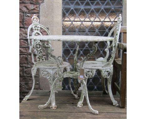 A Victorian style cream painted cast aluminium garden terrace table of circular form with decorative pierced detail, scrolled