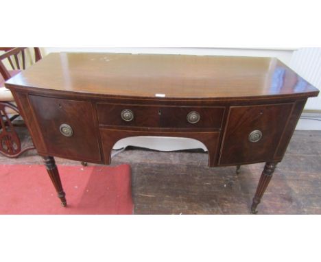 A Georgian mahogany bow fronted sideboard enclosing three drawers with central arch raised on turned, tapered and fluted supp