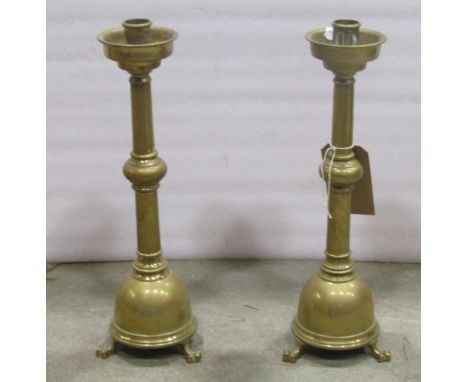 A pair of gothic revival brass candlesticks with knopped stems and domed bases with lions paw feet, 42 cm high (to be sold wi