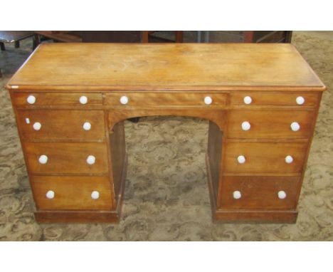 A Victorian satin birch kneehole twin pedestal dressing table/desk fitted with an arrangement of nine drawers with ceramic kn