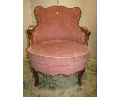 A pair of tub shaped drawing room chairs, with light pink upholstery, shaped outline and showwood frame with moulded detail r