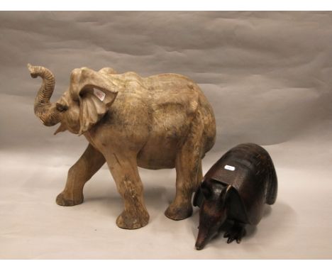 A weathered hard wood model of an elephant with raised trunk, 65cm long together with a model of an armadillo