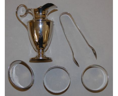 A silver cream jug, Sheffield 1902 of vase form, three silver napkin rings and a pair of sugar tongs