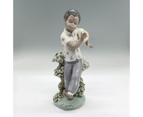 Glazed porcelain figure of a boy standing in front of a plant dancing and playing his drum. Lladro backstamp. Issued: 1982-19