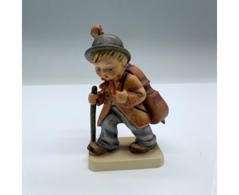 Hand-painted figurine depicting a boy with a walking stick and large cello on his back. Goebel backstamp on the bottom. Dimen