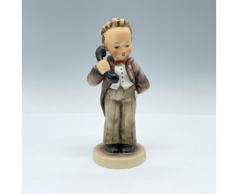 A ceramic figurine featuring a boy answering a phone call, dressed in a brown jacket and pants, a red bowtie, and a white shi