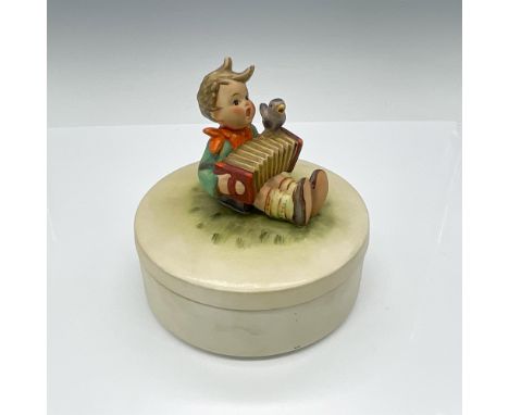 Hand-painted lidded powder box with a figure of a boy sitting on the top lid, depicted with his accordion and bird friend. Go