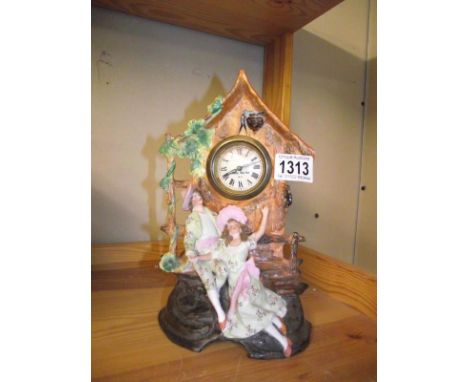 A bisque mantel clock depicting Courting Couple on bench with clock housed in a roofed folly COLLECT ONLY 