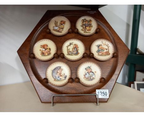 A Goebel/M J Hummel wooden wall plaque with 7 small Goebel collectors plates 