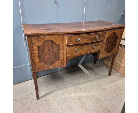An early 19th century ebony line inlaid mahogany sideboard with a curtain and brass rail back, the serpentine front with two 