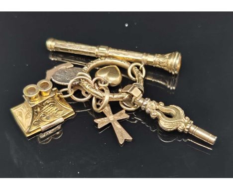 A small collection of antique gold charms suspended on a Victorian carved gold split ring, the charms include a stanhope in t