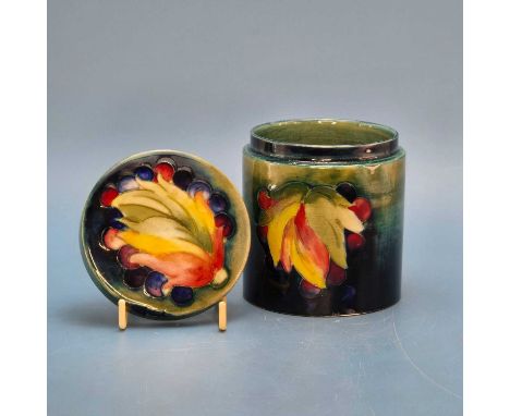 A Moorcroft cylindrical covered jar slip trailed with grapes surrounding leaves.   H 10cms.