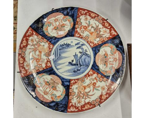 A Japanese Imari charger painted with alternating panels about an underglaze blue roundel of a sailing boat passing an island