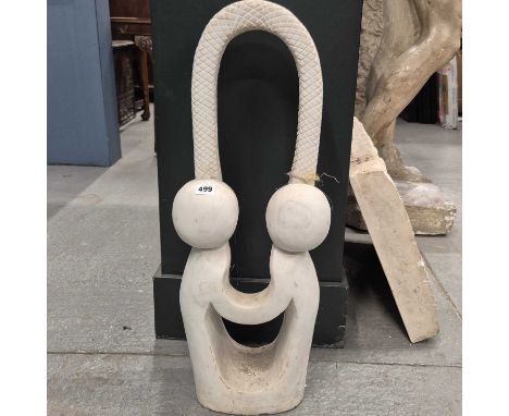 A white marble sculpture of a stylised couple below a round arch of snakeskin.   H 71cms