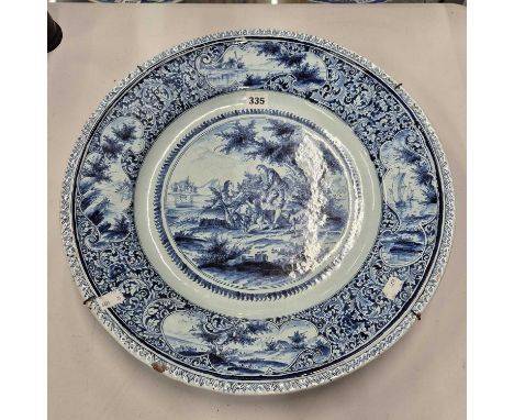 A Dutch Delft blue and white wall charger painted with a family by a shore handling a bird and its cage, the rim with shoresi