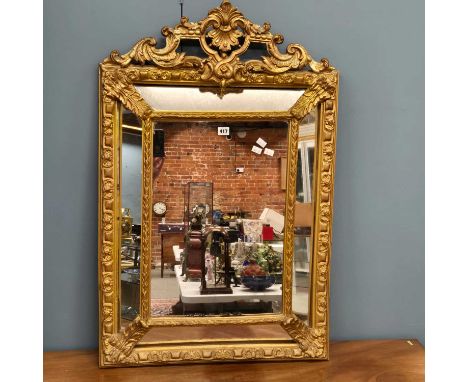 A gilt framed mirror, the central rectangular plate raised forward from four side plates below the pierced foliage and bracke
