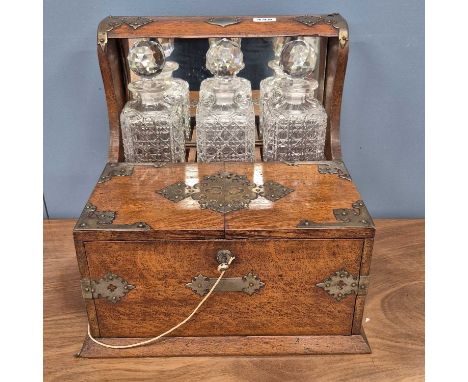 An electroplate mounted oak three bottle spirit tantalus, smoking and games compendium, the playing cards printed for Manikin