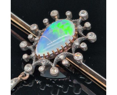 An antique opal and diamond ornate bar brooch. The central teardrop opal is surrounded by an array of old-cut diamonds of var