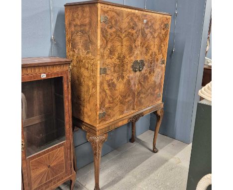 An electrically lit walnut drinks cabinet on a stand with cabriole legs on carved bun feet.   W 108 x D 44 x H 162cms