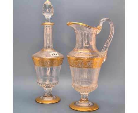 A St Louis glass decanter and matching jug, each gilt with a guilloche foliage band below the shoulders, Gusberti retailer's 