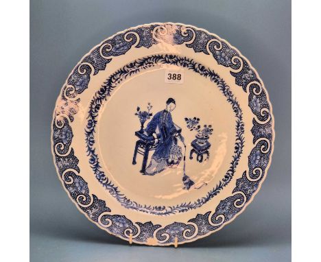 An 18th century Chinese blue and white dish painted with a lady standing by tables dangling the tassel from her fan for a cat