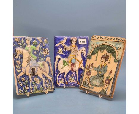 Four various Qajar relief moulded polychrome tiles, two depicting equestrian figures hawking. 20 x 14cms. Another man kneelin
