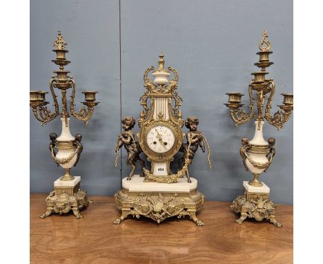 An ormolu, bronze and white marble clock garniture, the lyre shaped clock supported by two satyrs standing below the urn cres