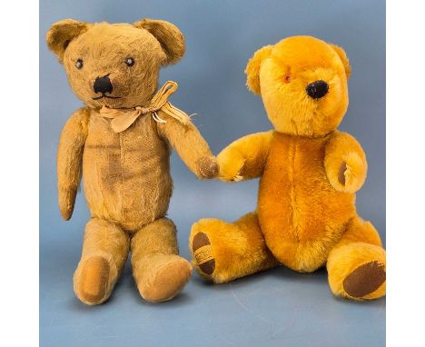 A Merrythought teddy bear together with another bear, earlier with a blank metal button in his right ear and a further joined