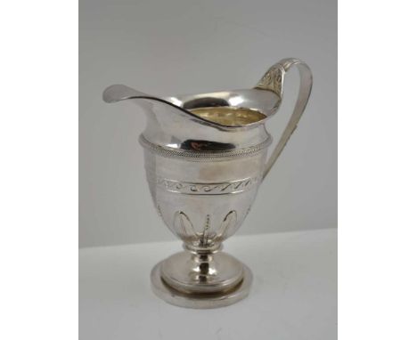 JOHN SCHOFIELD A GEORGE III SILVER MILK JUG, helmet form, cast leaf decoration to handle and tapering body, on circular platf