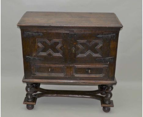 AN OAK CUPBOARD ON STAND, part 17th century, the rectangular plank top over a pair of panel doors with iron hinges, opening t