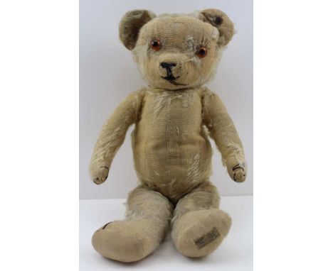 A "MERRYTHOUGHT" TEDDY BEAR, worn blonde plush with glass eyes, bears the early "Hygenic Toys" label c.1930, 42cm high, in kn