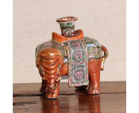 A Chinese famille rose candlestick, late 19th century, in the shape of an elephant carrying a vase, the saddlecloth decorated