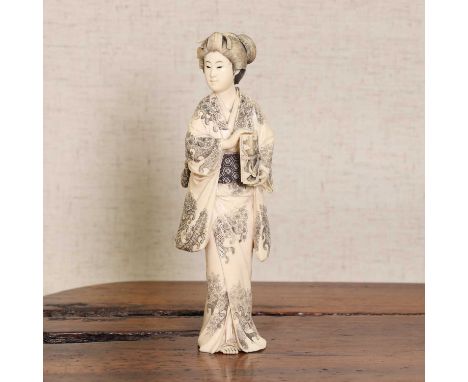 A Japanese ivory okimono,Meiji period (1868-1912), carved as a lady standing in an elaborate kimono, incised with cherry blos