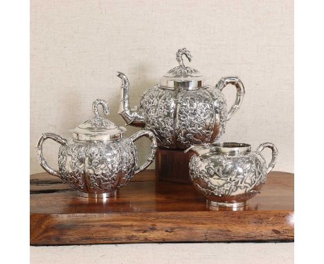 A Chinese silver tea set,c.1900, comprising: a teapot and cover, a sugar bowl and cover, and a milk jug, all of globular form