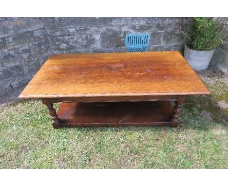 A large oak coffee table, of rectangular form, raised on turned legs with shelf under, 58.5ins x 31ins x 17.5ins