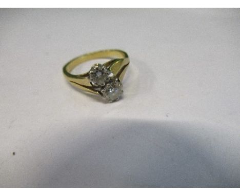 A two stone diamond cross over ring, stamped '22ct', the brilliant cuts of approximately 0.25 and 0.15 cts, finger size H 1/2