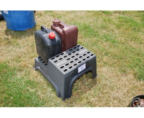 A plastic step and two plastic water containers.