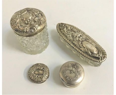 TWO SILVER TOPPED GLASS DRESSING TABLE ITEMSand another loose silver top, all with embossed scroll and floral decoration; tog