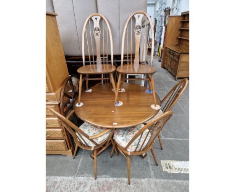 An Ercol elm extending dining table and six swan back chairs, including two carvers.  