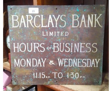 A brass metal plaque with Barclays Bank hours on one side and Ernest Cowpe, Surveyor and Building Society agent on other side